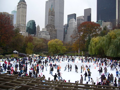 crowds ice skating in NYC with skyscrapers in the background