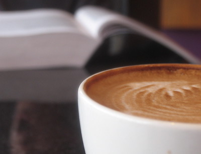 close-up of cup of espresso with open book in the background