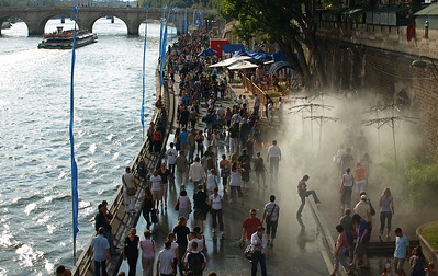 people under sprinklers near river