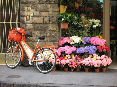 orange bike next to flower market stall