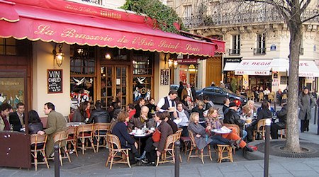 people crowded at outdoor tables at a cafe