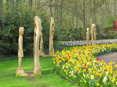 wood sculptures next to rows of tulips