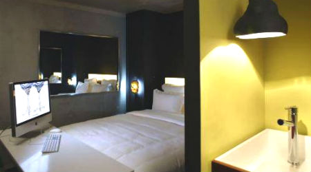 white guest room with yellow accent wall at Mama Shelter Paris