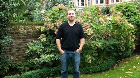 Aled Rees, owner of Ridgemount Hotel London, standing by flower bushes