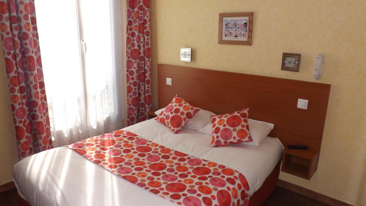 hotel room with white, red, and orange bedding and matching curtains