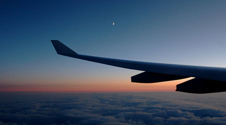 view of plane wing over clouds at sunset