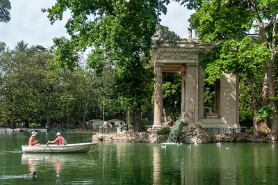 people rowing boat past ancient building with columns
