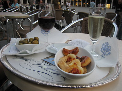 bowl of pastries and bowl of olives near two glasses of wine