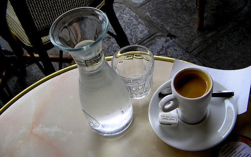 Carafe of water and cup of coffee on table