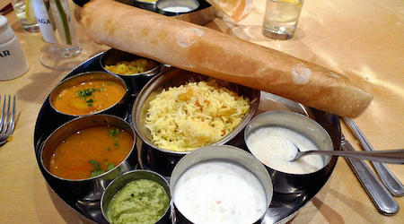 Pilau rice with a variety of vegetarian curries, a dosa pancake, and a rice pudding