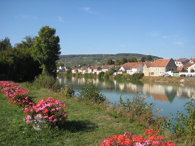 River Marne lined with grass and flowers on one side and small homes on the opposite side