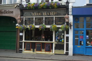 The Harp pub exterior with chalkboard signs and hanging pots of flowers