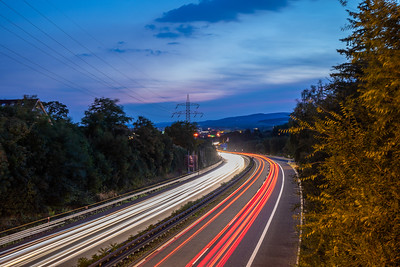 blurred headlights and tail lights on a road at dusk