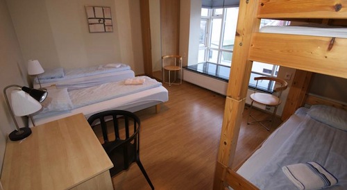 white hotel room with two single beds and set of bunk beds