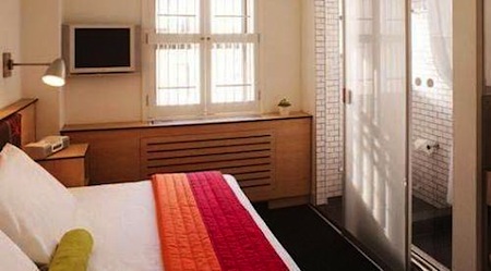 beige hotel room with red and orange bedding