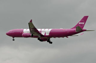 Wow Air purple plain flying through gray skies