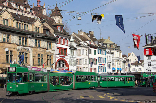 green tram driving through Basel