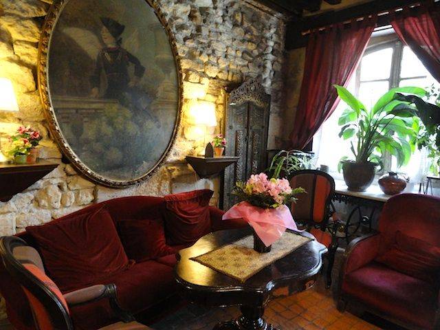 one of many charming Paris hotels, Hotel Esmeralda's lobby with stone walls and red velvet sofa
