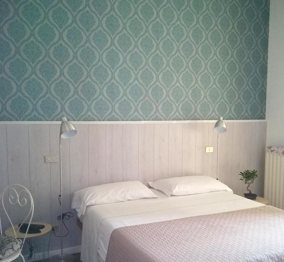 a hotel room with light blue patterned wall and white double bed