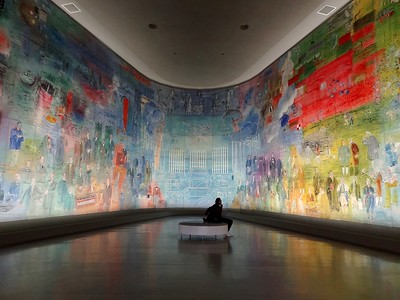 person sitting in room with walls covered in modern artworks
