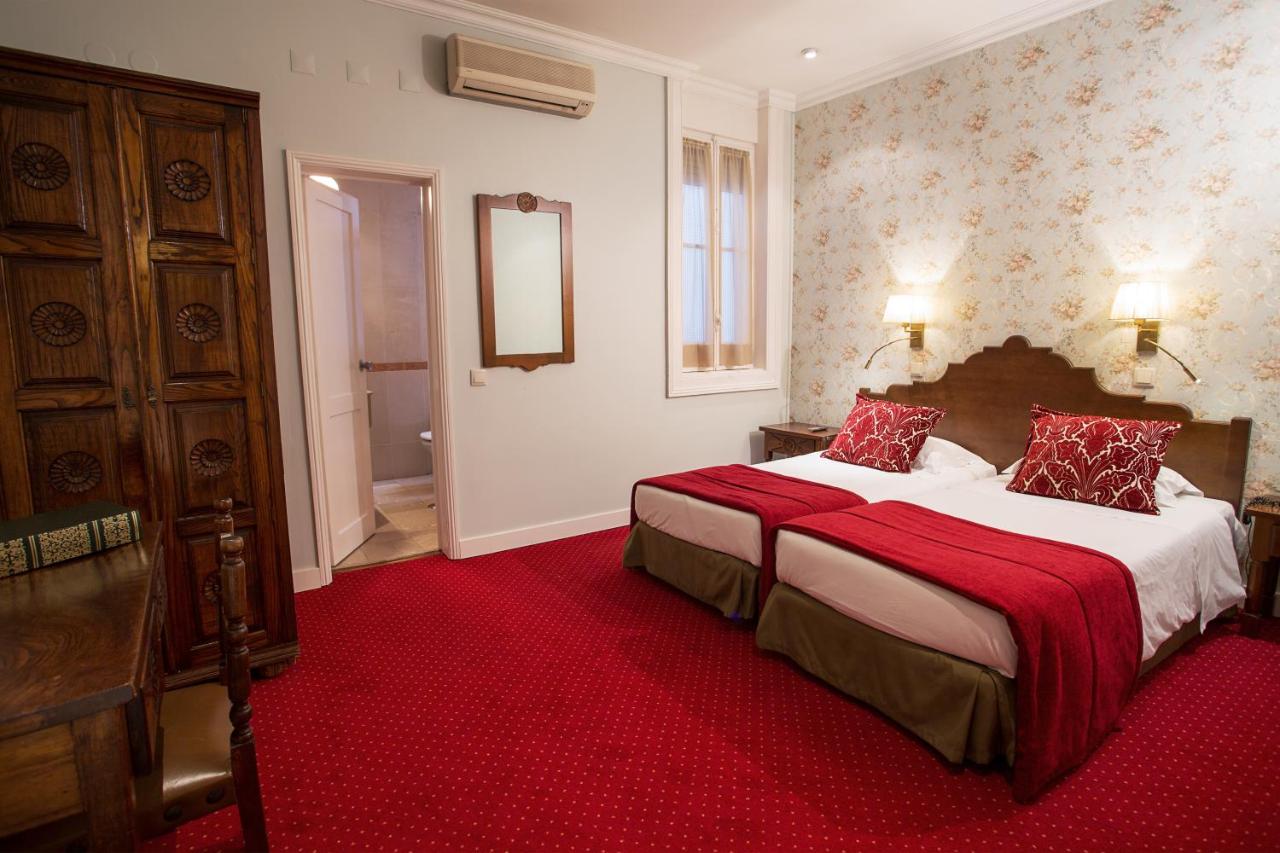 hotel room with red carpet and gold patterned wall paper plus vintage wood furnishings