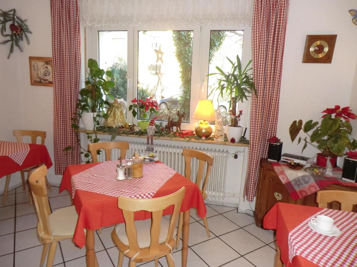 breakfast room with tables in red tablecloths and plants on a windowsill