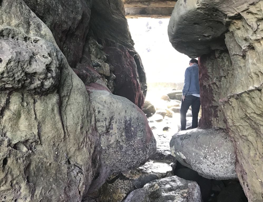 person walking on rocks in a beach cove