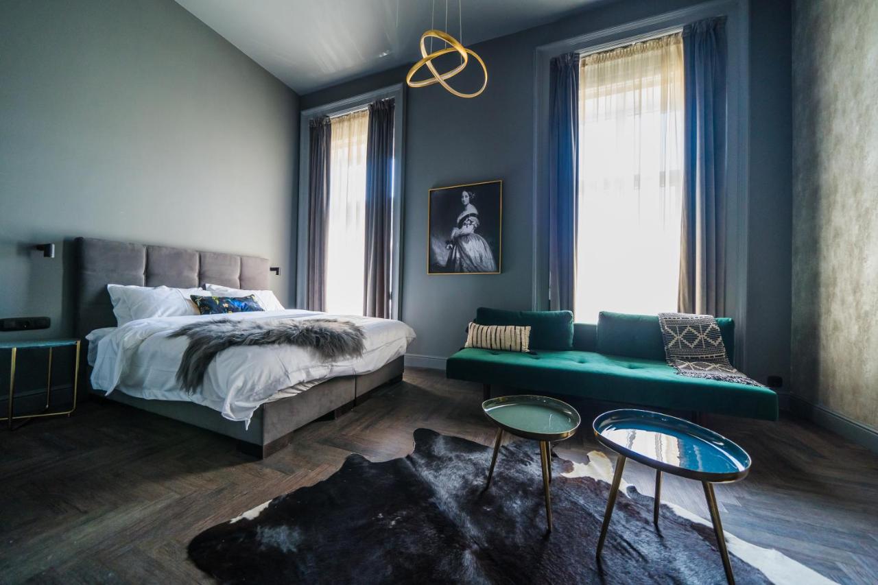 hotel room with dark gray walls, teal sofa, and large bed with fur blanket