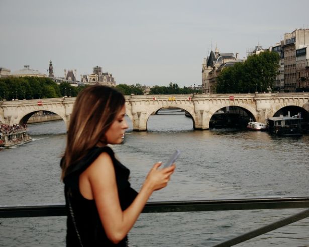 A woman is checking her phone while walking, in Paris