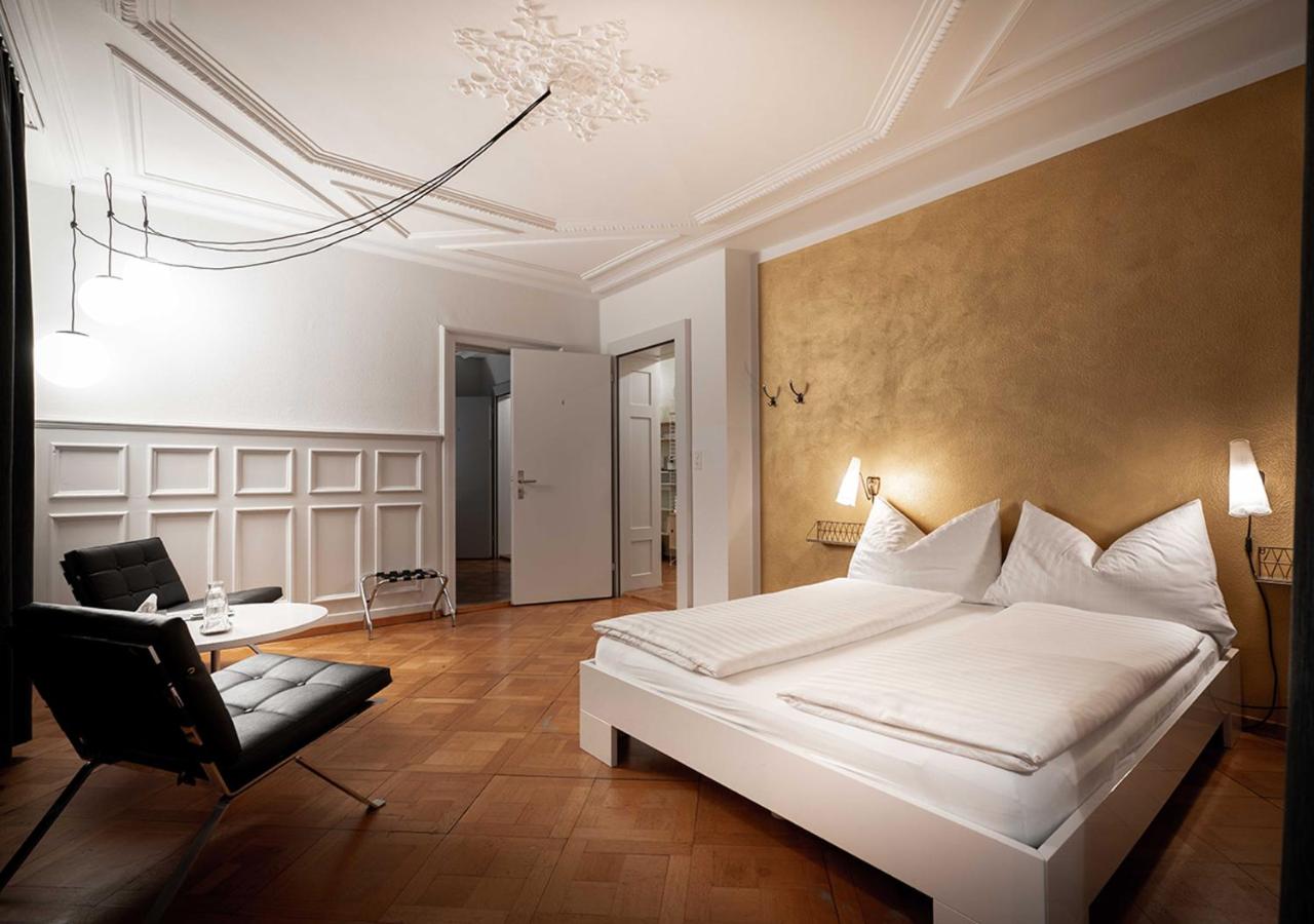 large hotel room with one wallpapered wall and large white bed at Zum Guten Gluck, one of the best budget hotels in Zurich
