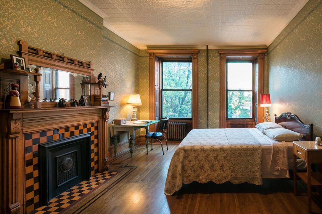 hotel room with patterned wallpaper and checkered fireplace at Harlem Flophouse