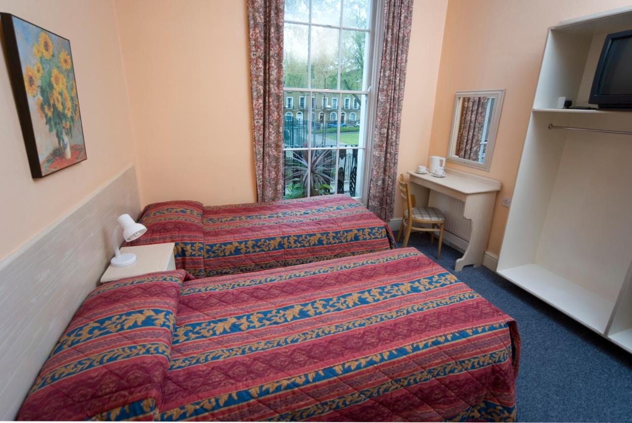 two beds with striped comforters in peach-colored hotel room