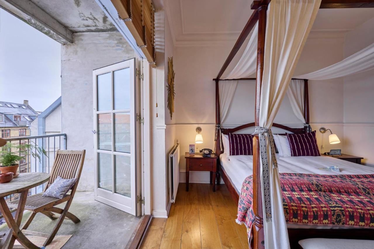 hotel room with striped bedding and canopy on bed and doors open to a balcony
