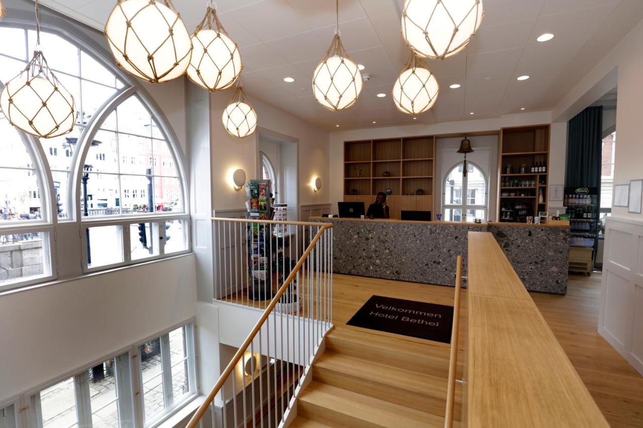 Hotel Bethel lobby with wood steps, wood floors, gray and wood reception desk, and netted hanging lights