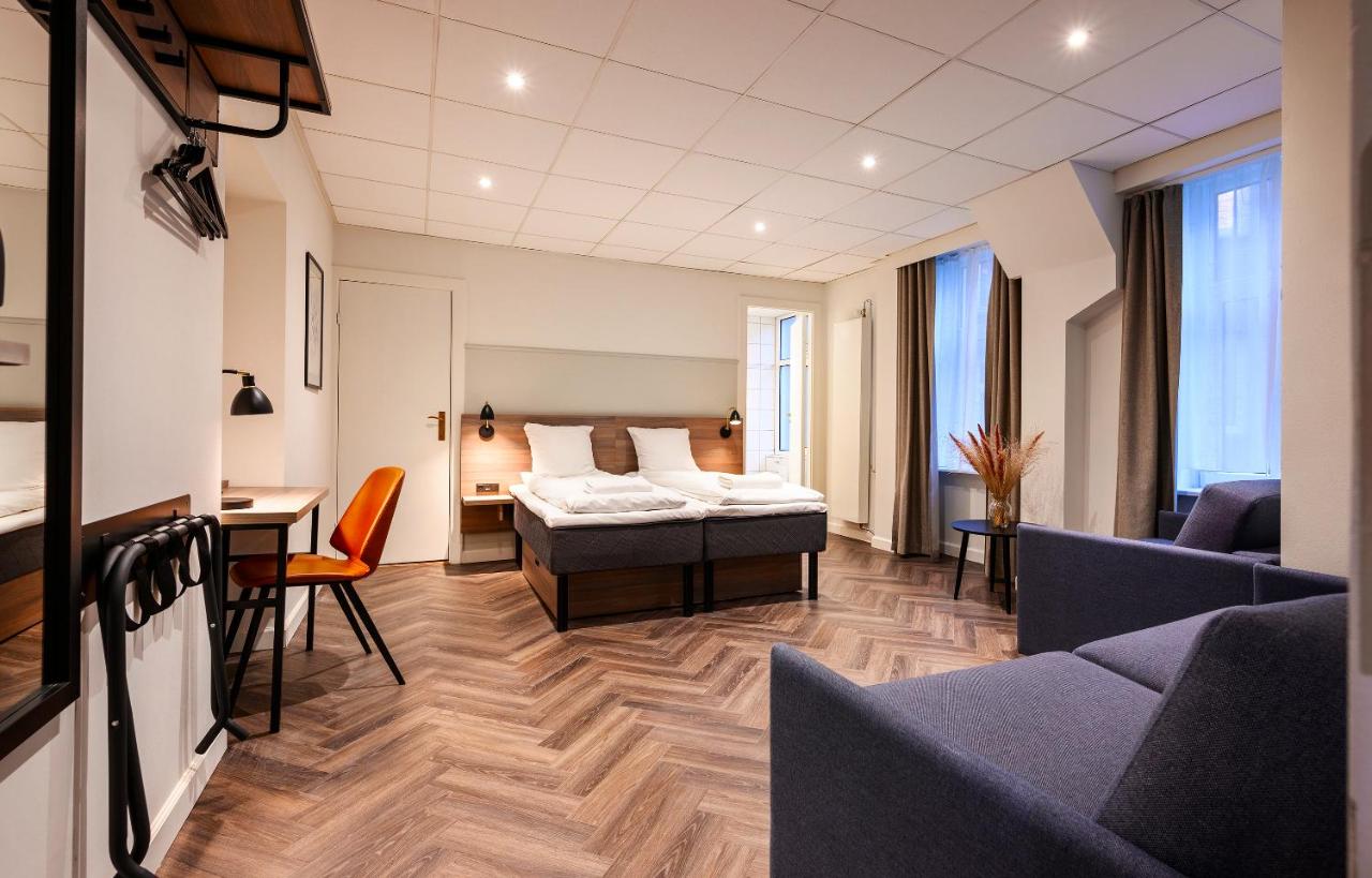 hotel room with herringbone wood floors, white bed, wood headboard, and white walls at Hotel Saga, one of the best budget hotels in Copenhagen