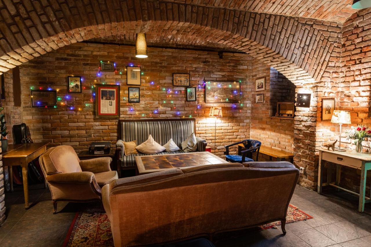 brick-lined room with several sofas and colorful string lights